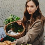 Young woman shopping at Erfurt farmers market, holding basket with fresh vegetables. Capturing local shopping culture.